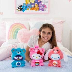 Three Care Bears Funsize plush with a young girl displayed in a lifestyle setting, surrounded by colorful decorations, promoting a playful and cheerful atmosphere.