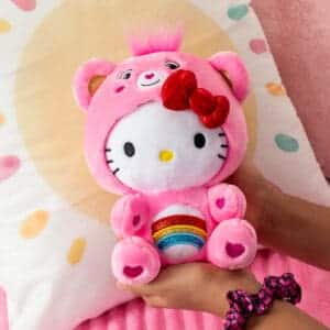 Plush Hello Kitty dressed as Cheer Bear a young girls hand.